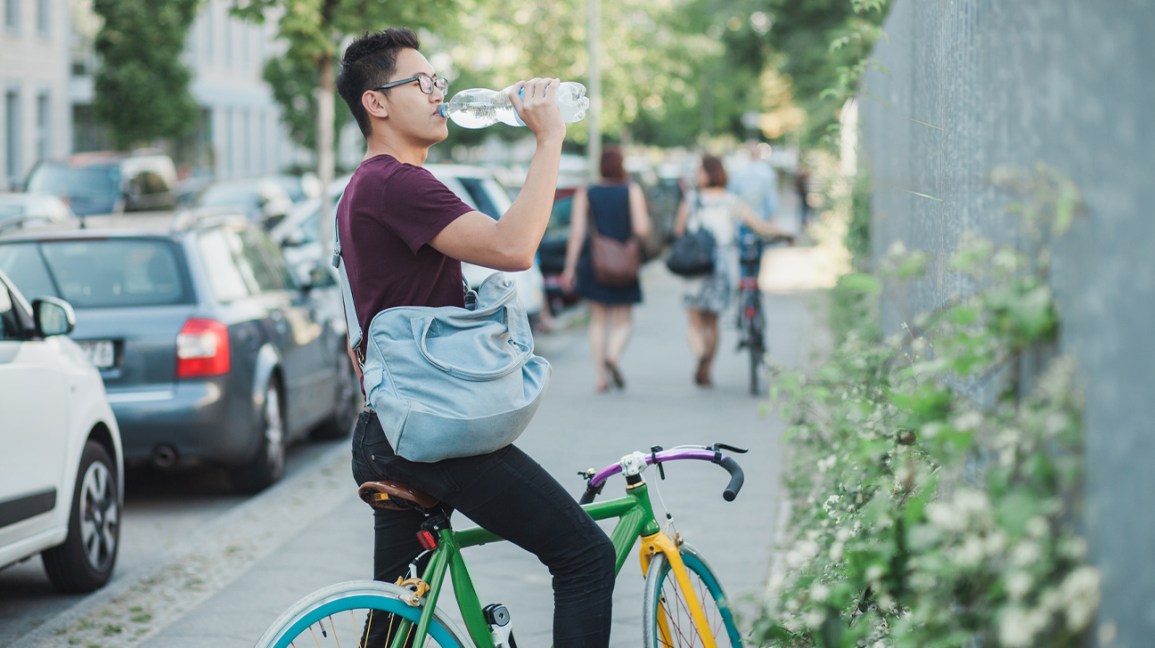 man on bike drinking from one-liter water bottle